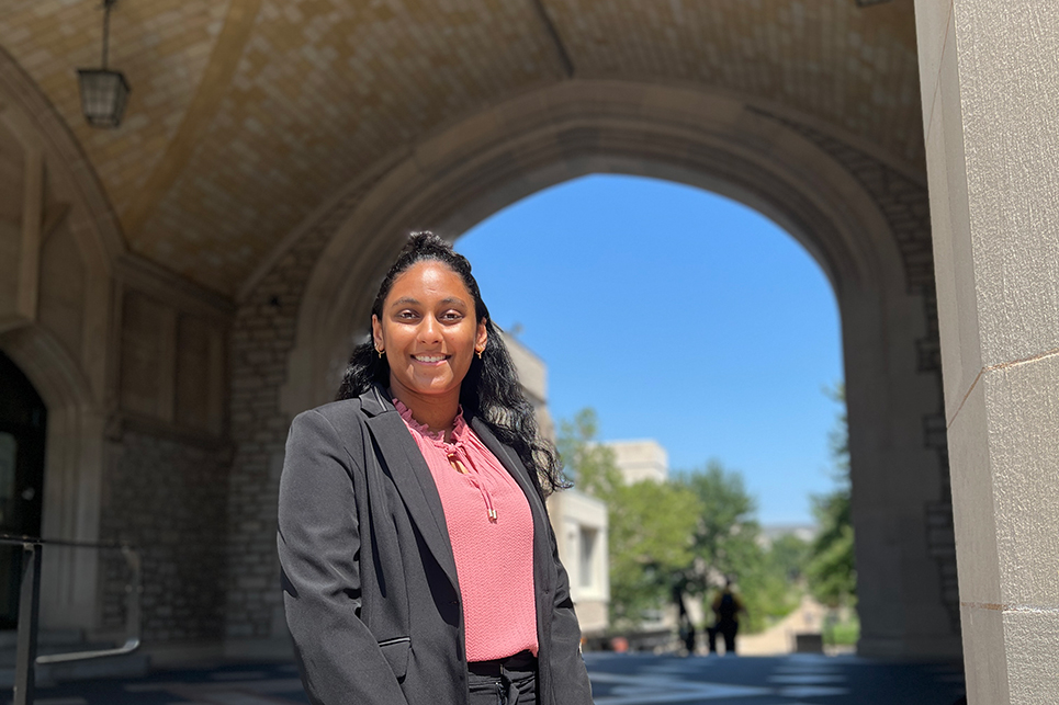 A young woman stands under the arch of Memorial Union at the University of Missouri